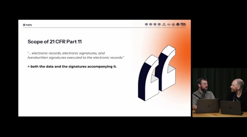 Presentation slide showing Scope of 21 CFR Part 11 covering electronic records and signatures, with two men seated at a table
