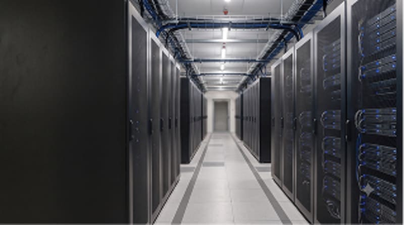 Data center aisle with rows of server racks and overhead cable trays under bright lighting.
