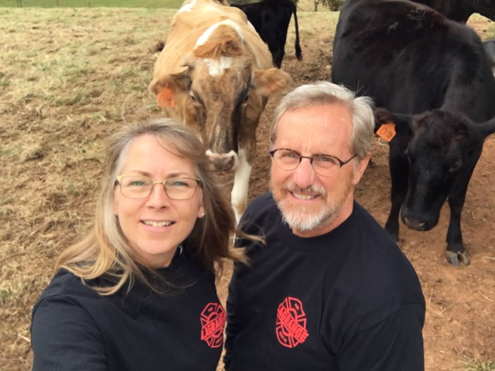 Ben and Karen Sargent smiling in a pasture, with cattle behind them