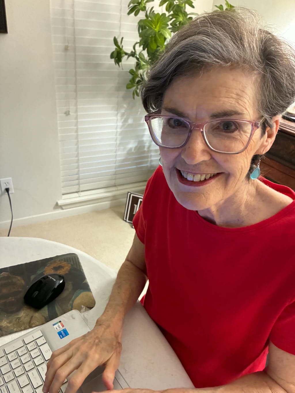 Patricia Rebsch, smiling, at her desk with her hand on the keyboard