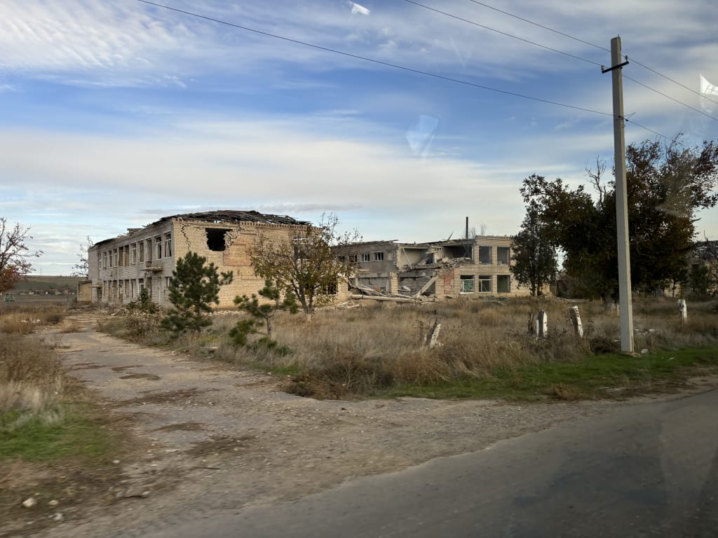 The shell of a school building, its walls and roof torn open by shelling.