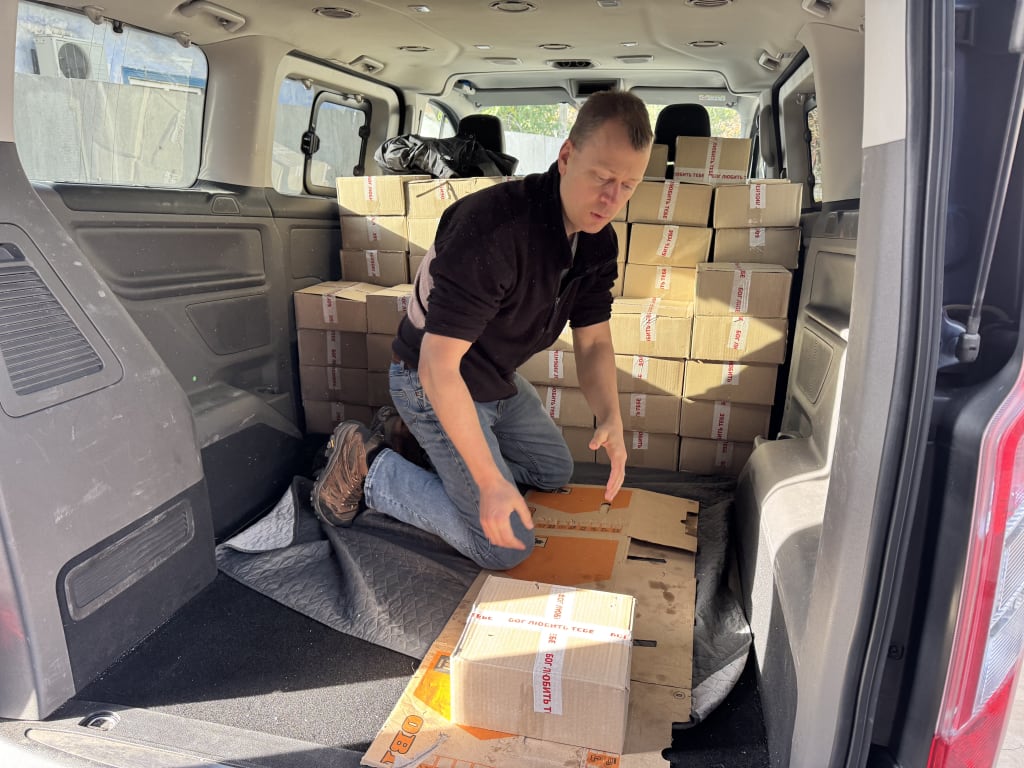 Nathan Day stacks cardboard aid boxes into the back of a van.