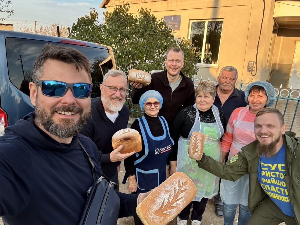 The team poses with a group of local bakers, several holding loaves of bread.