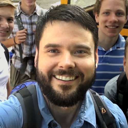 Smiling, with young people from a summer team behind him.