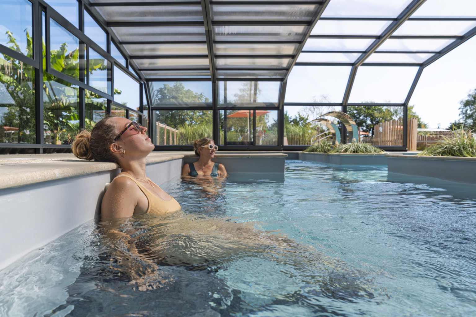 2 adults relaxing in the covered pool at Camping Parc Sainte-Brigitte, Brittany
