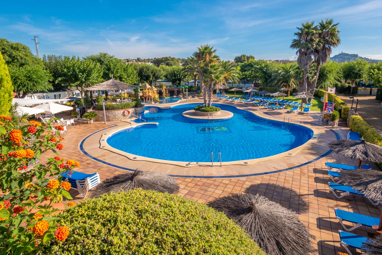 Central pool surrounded by shrubs and sunloungers, la Masia campsite, Blanes, Costa Brava