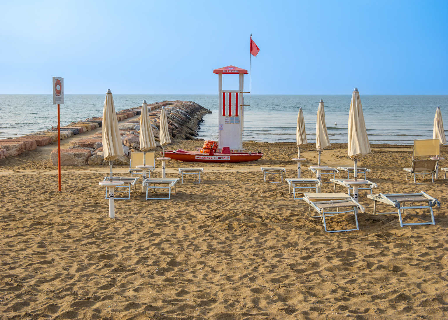Sunloungers and parasols on the beach by the pier at Portofelice camping village, near Venice