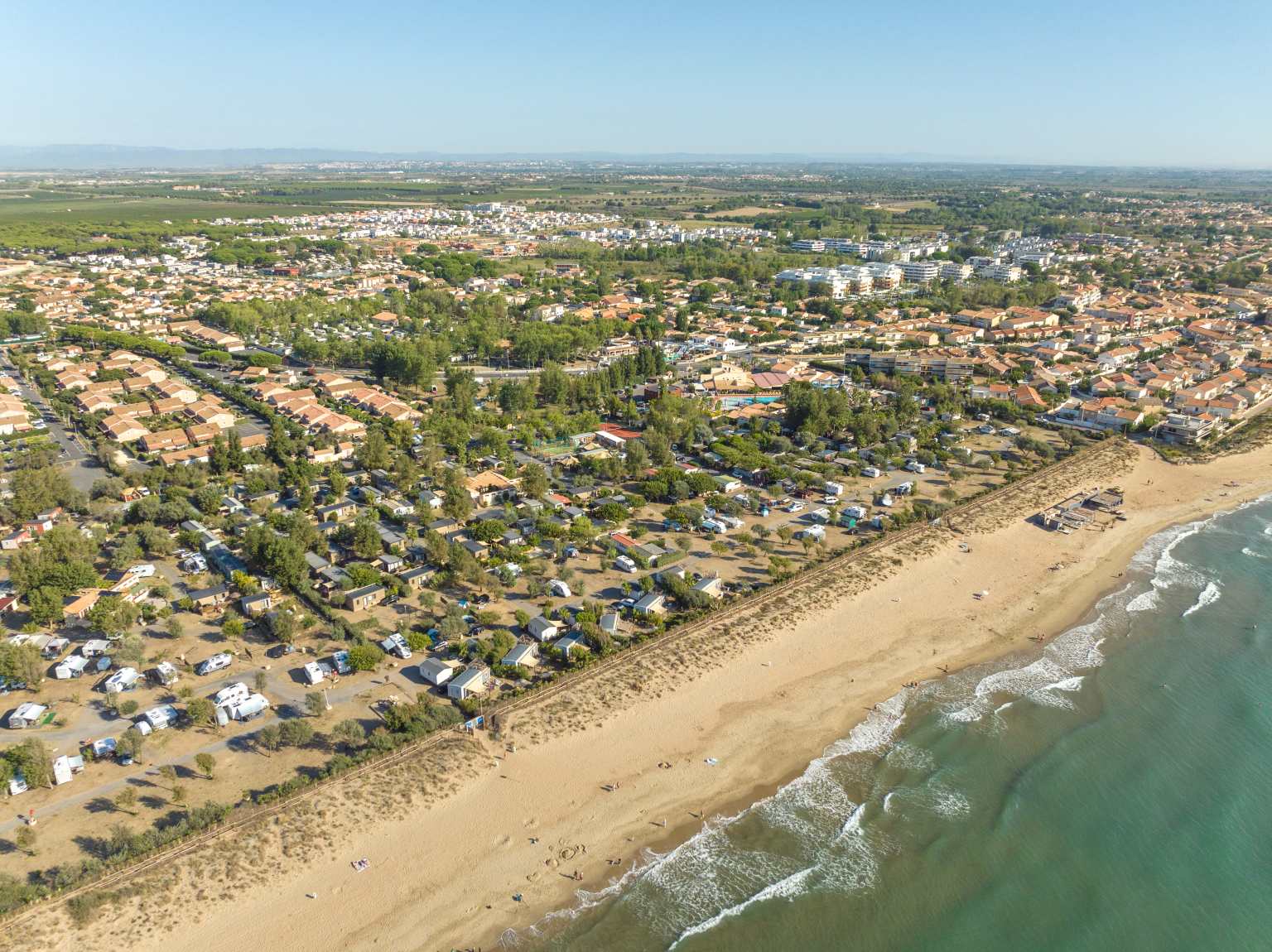 Aerial view of the long sandy beach next to Plage et le Bord de Mer campsite, Languedoc