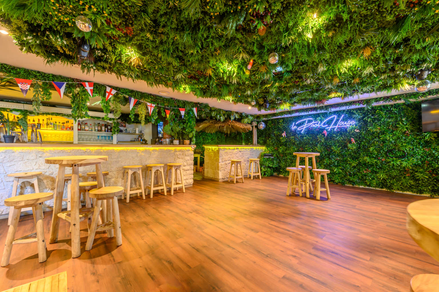 Indoor bar with walls covered in fake greenery and high stools at La Croix du Vieux Pont