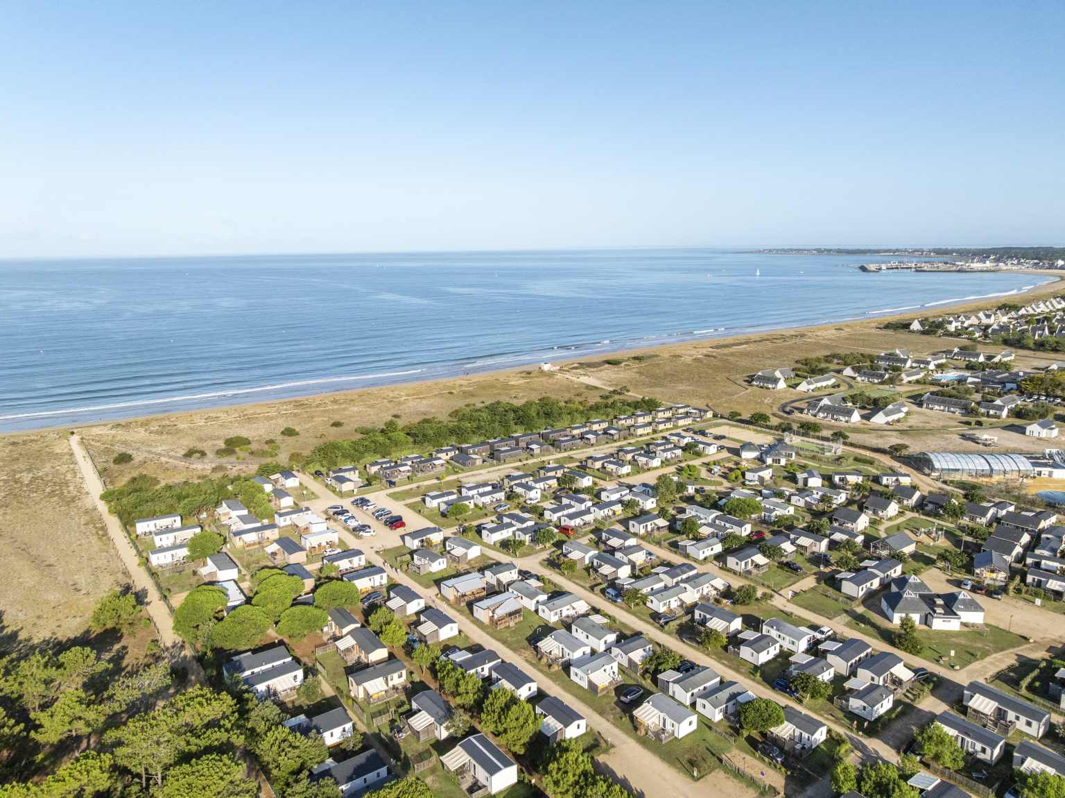 Aerial view of holiday home pitches and the path to the beach, adjacent coastline at Les Chardons Bleus de la Turballe campsite, Brittany