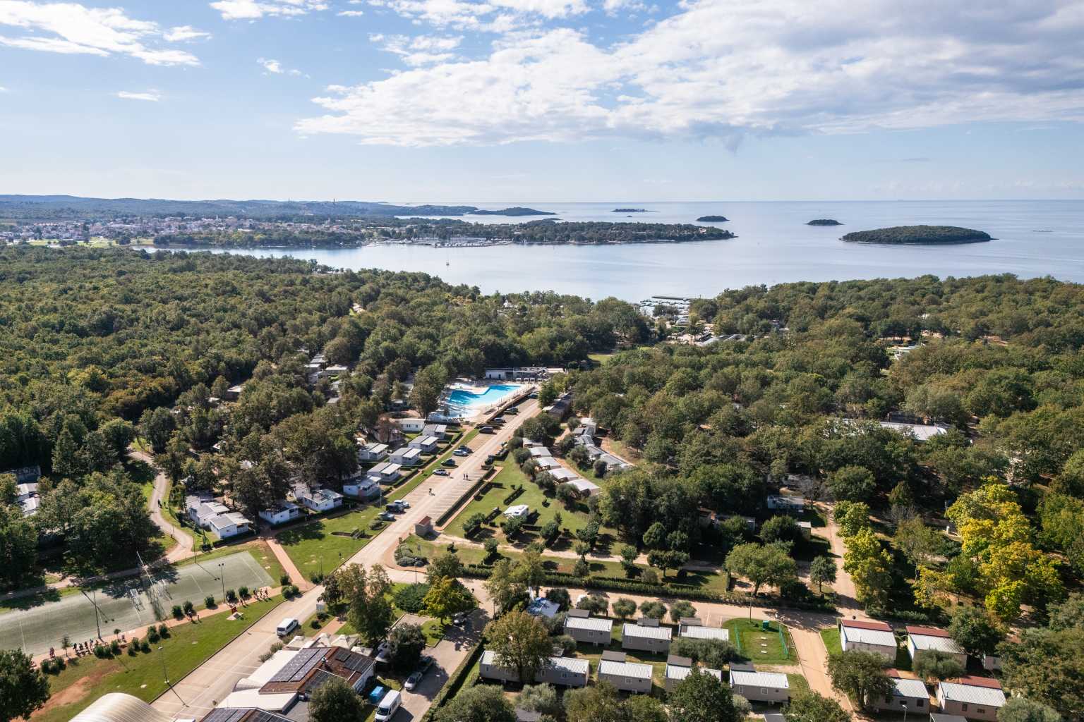 Aerial view of woodland and holiday home pitches by the sea at Bijela Uvala campsite, Porec, Croatia