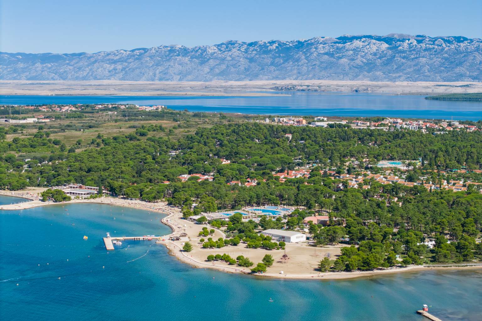 Aerial view of Zaton Zaton Holiday Resort lying on a flat peninsular near Zadar, in Dalmatia, Croatia, the sea in the foreground, mountains in the distance, with the sea beneath them 