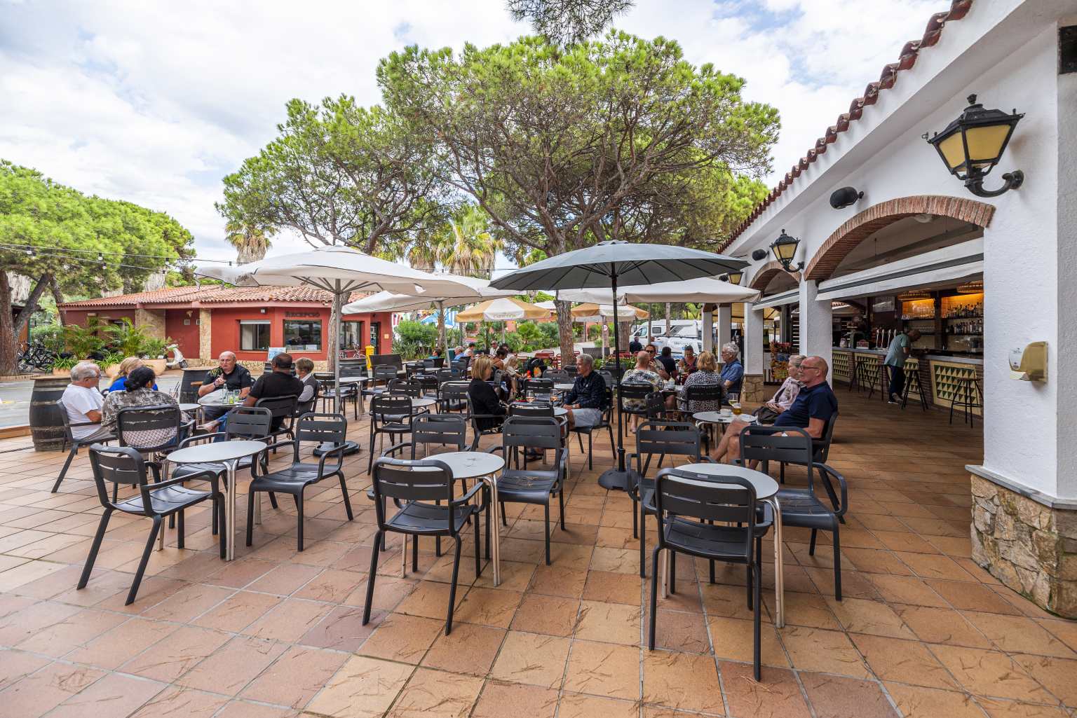 People sat at the tables on the restaurant terrace courtyard at Bella Terra campsite, Costa Brava