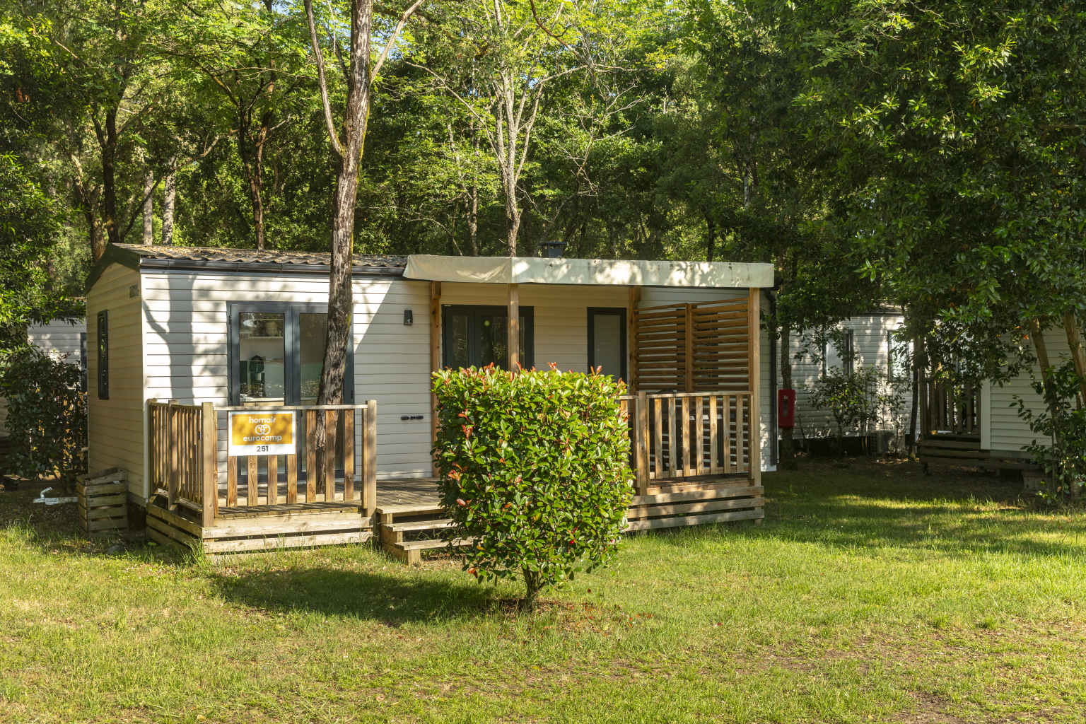 Holiday home acccomodation with covered decking under trees at Lou Pignada campsite, Ondres Landes