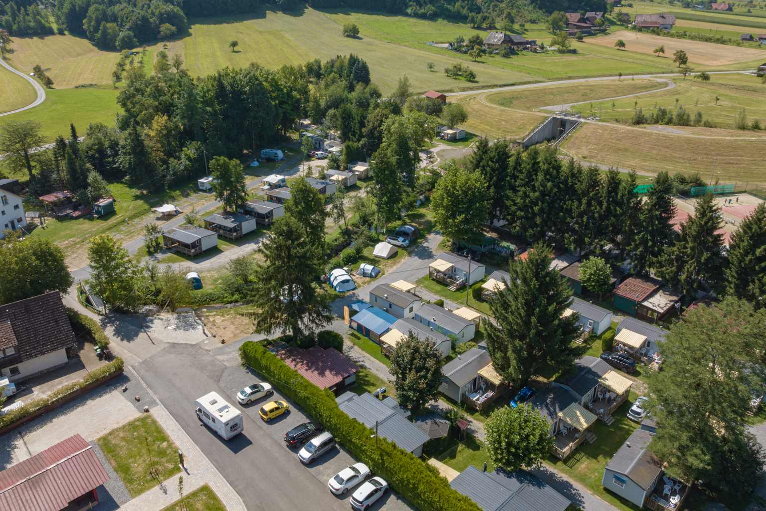Aerial view of the holiday home pitches, backed by trees, and fields behind, at Kinzigtal campsite in the Black Forest in Germany