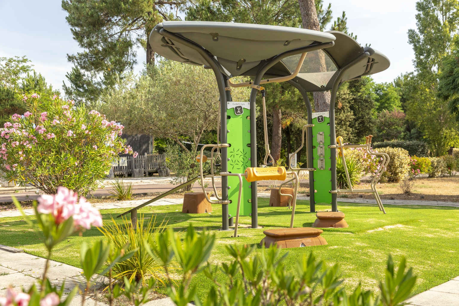 Pointe du Medoc campsite outdoor gym area on a lawn, surrounded by hedges and plants