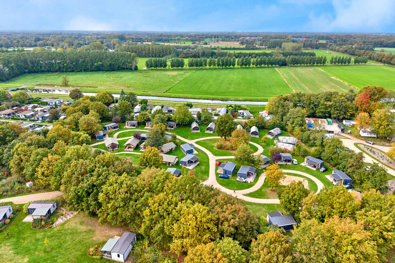 Aerial view of holiday homes and campsite road, and woodland, canal and fields at Camping De Twee Bruggen in the Netherlands