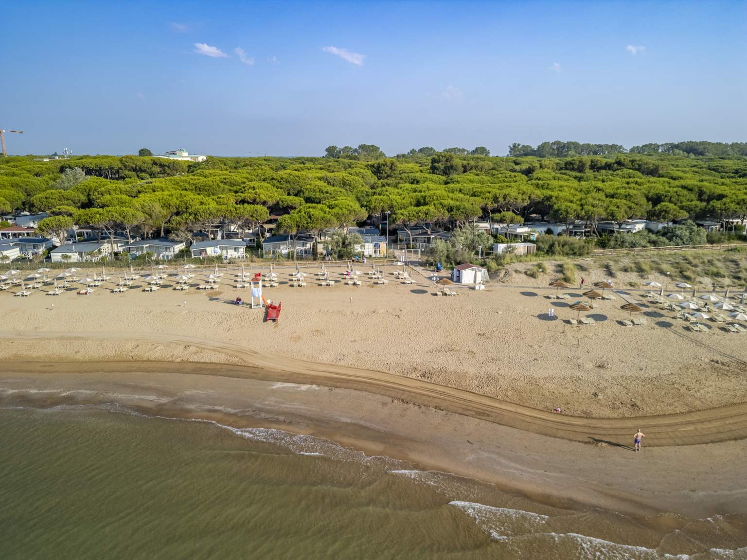 Aerial view looking from the sea towards the beach, with pitches under the trees at Jesolo Mare Camping Village, Adriatic