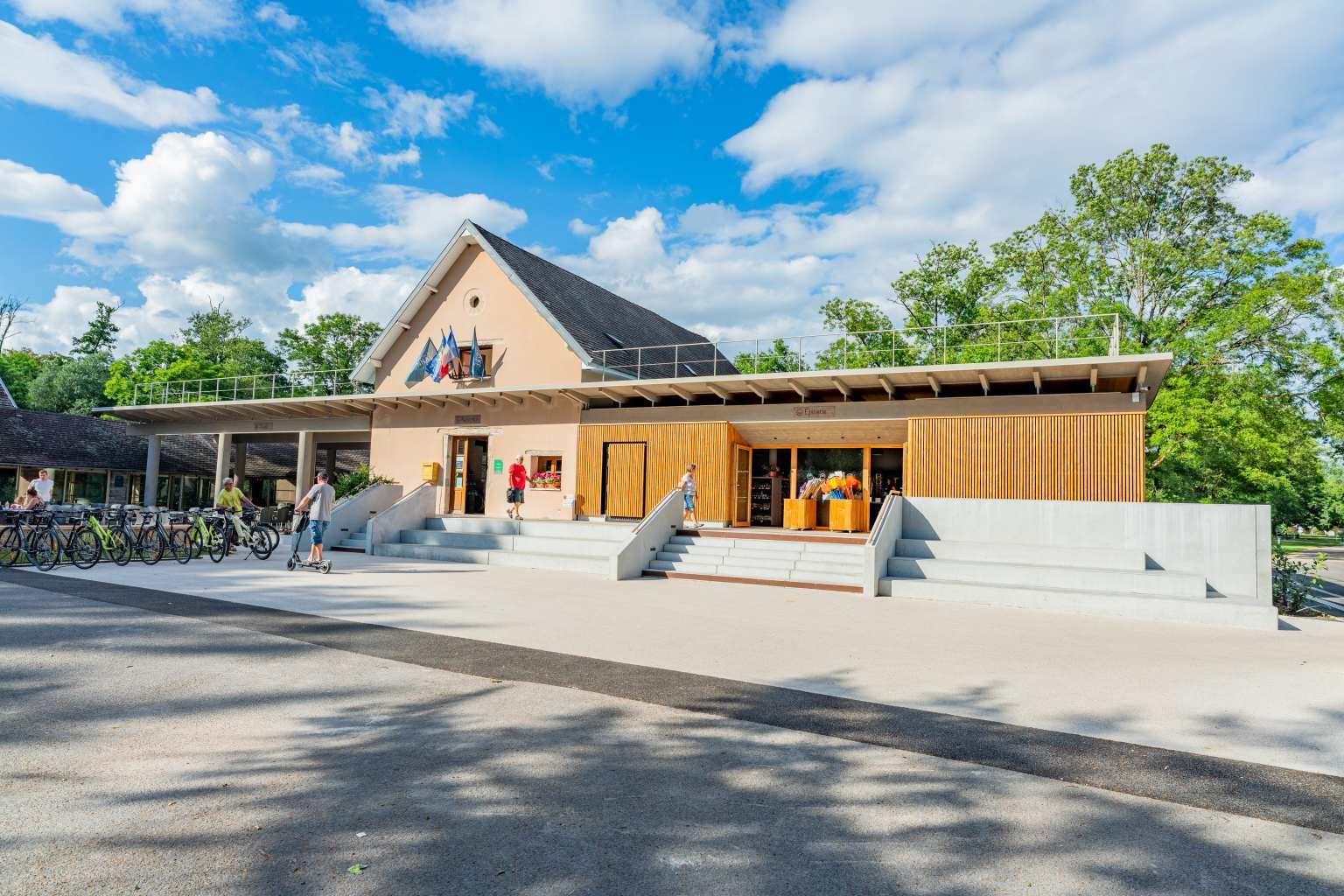 Single storey shop building with steps in front and bikes for hire lined up on the left, at Val de Bonnal campsite in the Jura