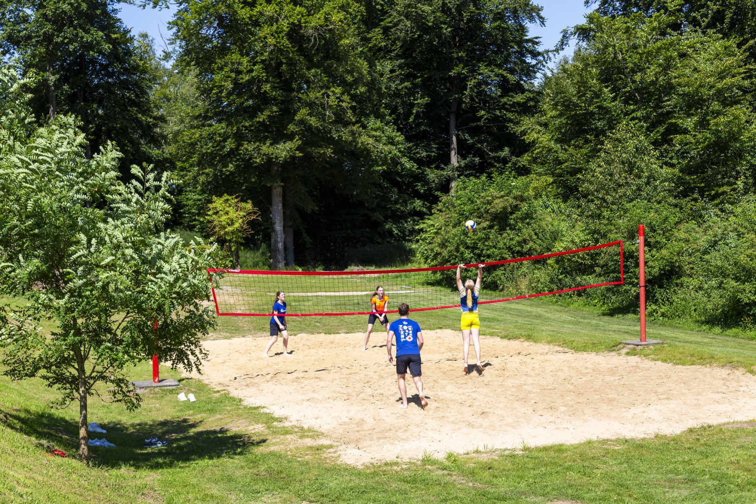 4 teenagers playing volleball on the outdoor court at Hu Birkelt Village campsite in Luxembourg