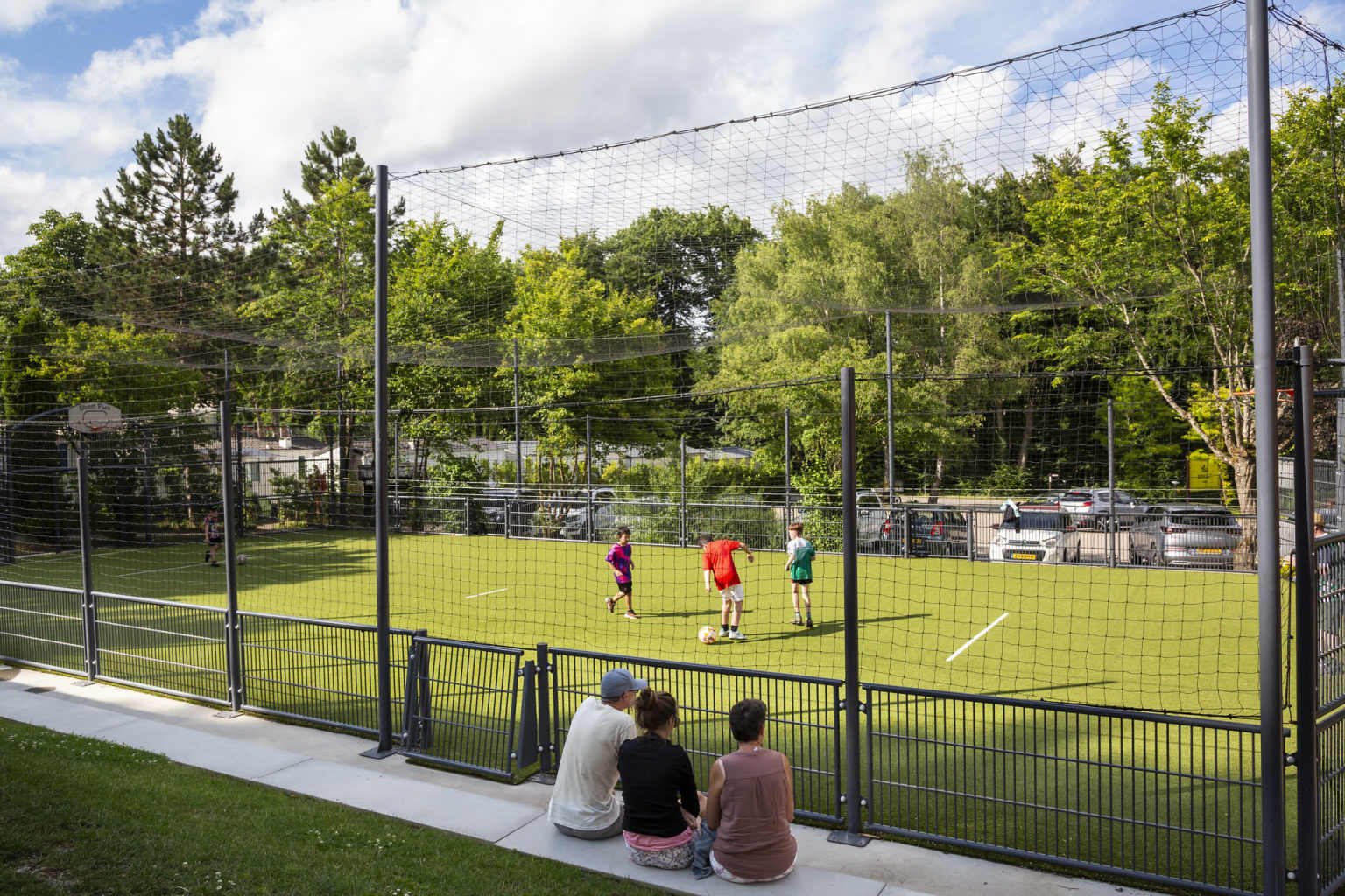 Kids playing football on the multi sports field at Hu Birkelt Village campsite in Luxembourg