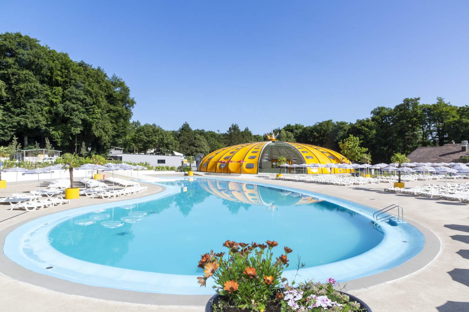 Curving outdoor pool and dome shaped indoor pool (cover partially open) at the far end, at Hu Birkelt Village campsite in Luxembourg
