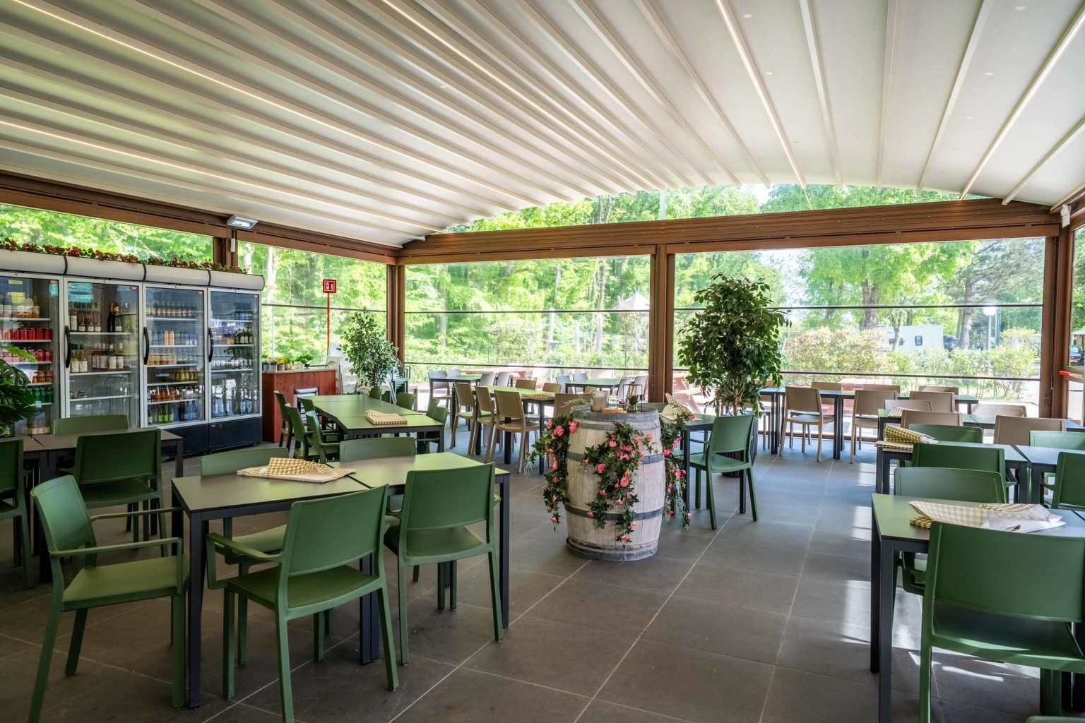 Restaurant tables in airy room with wall to wall windows at Hu Birkelt Village campsite in Luxembourg