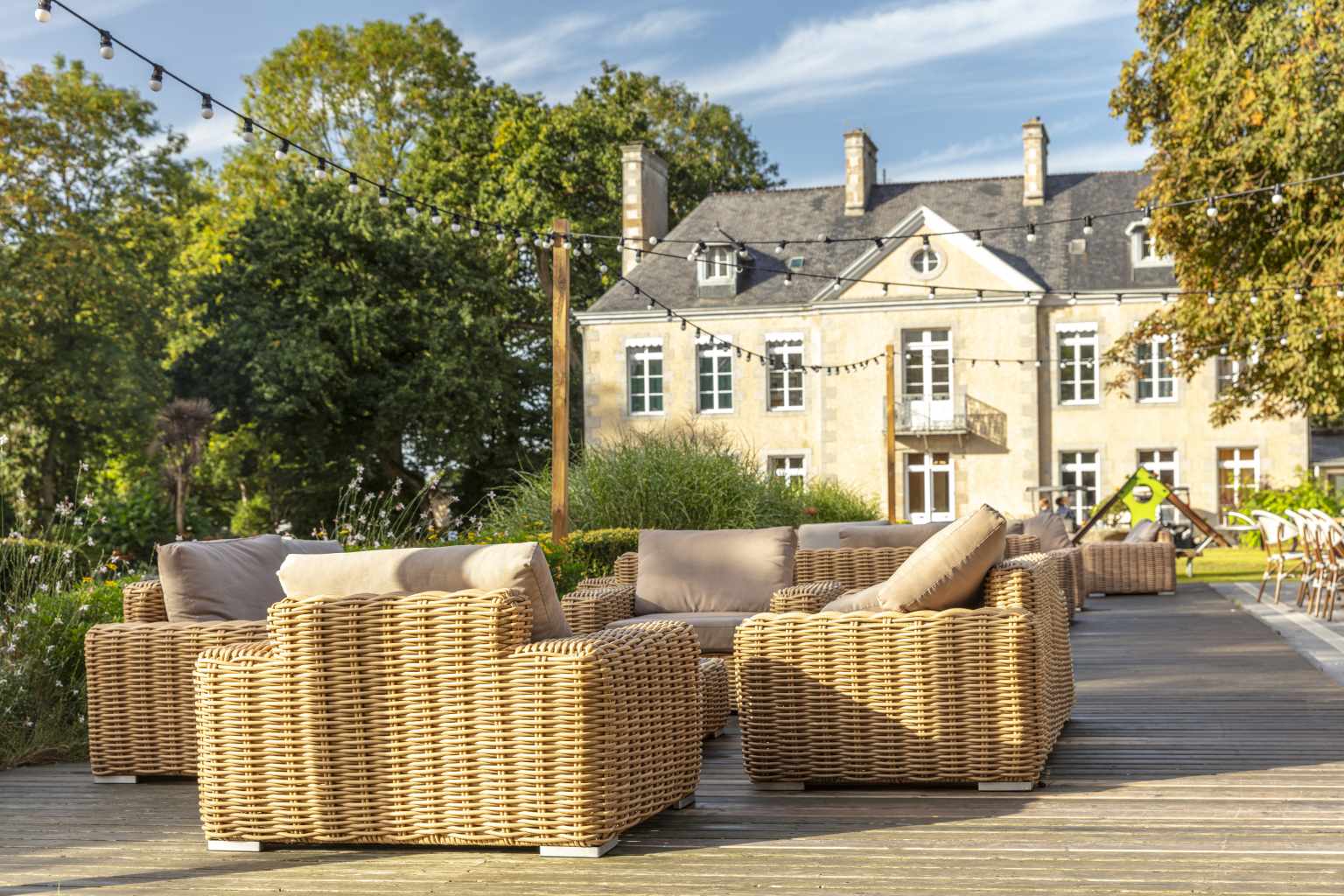 Comfortable sofa seating on wooden decking with chateau views at Chateau les Eaux campsite, Brittany