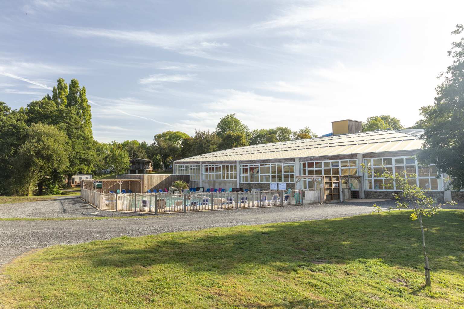 Looking across the lawn and road to the outdoor pool and indoor pool building at Chateau les Eaux campsite, Brittany