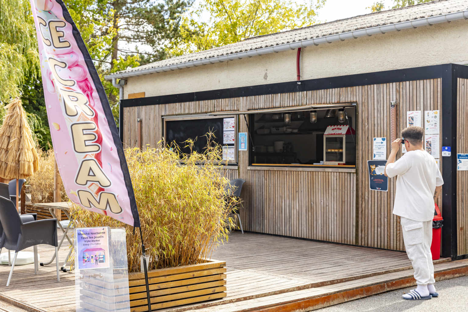 Man standing by the decking next to the snack bar at Les Fontaines campsite, Ivry-la-Bataille, France