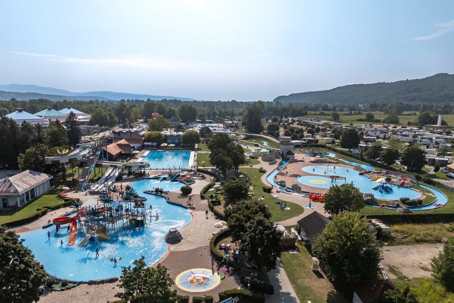 Aerial view of the kids lagoon with large splash park feature slide, beyond Olympic pool, at Terme Čatež campsite in Slovenia