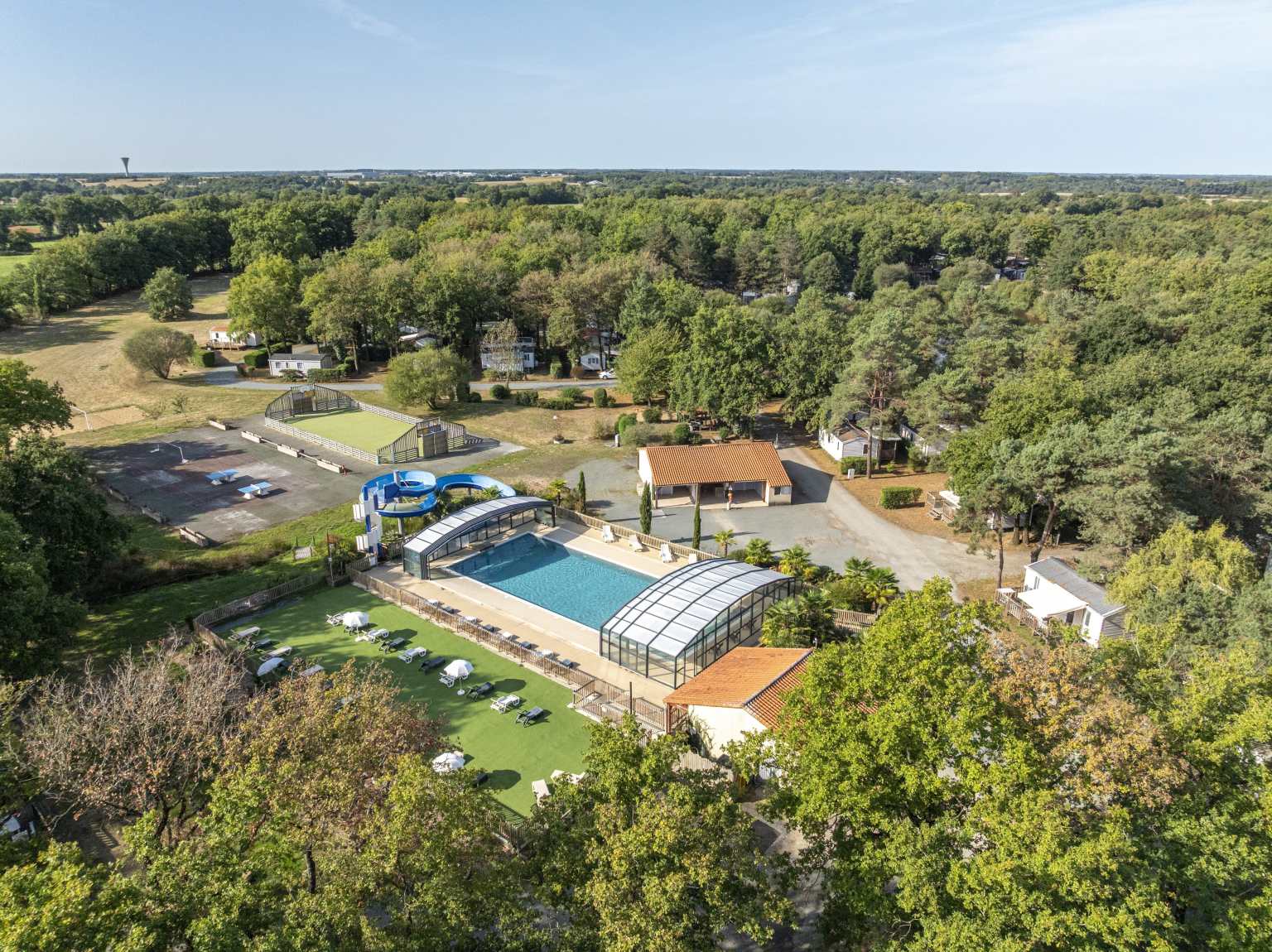 Aerial view of the covered pool surrounded by woods at Coeur de Vendée campsite in France