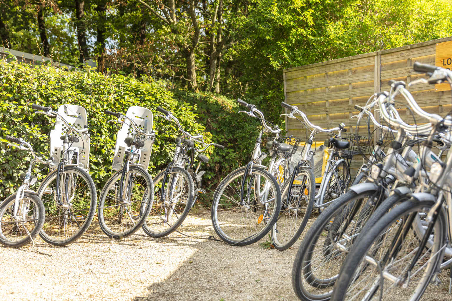 Adults bikes lined up for hire including two bikes with baby seats at Coeur de Vendée campsite in France