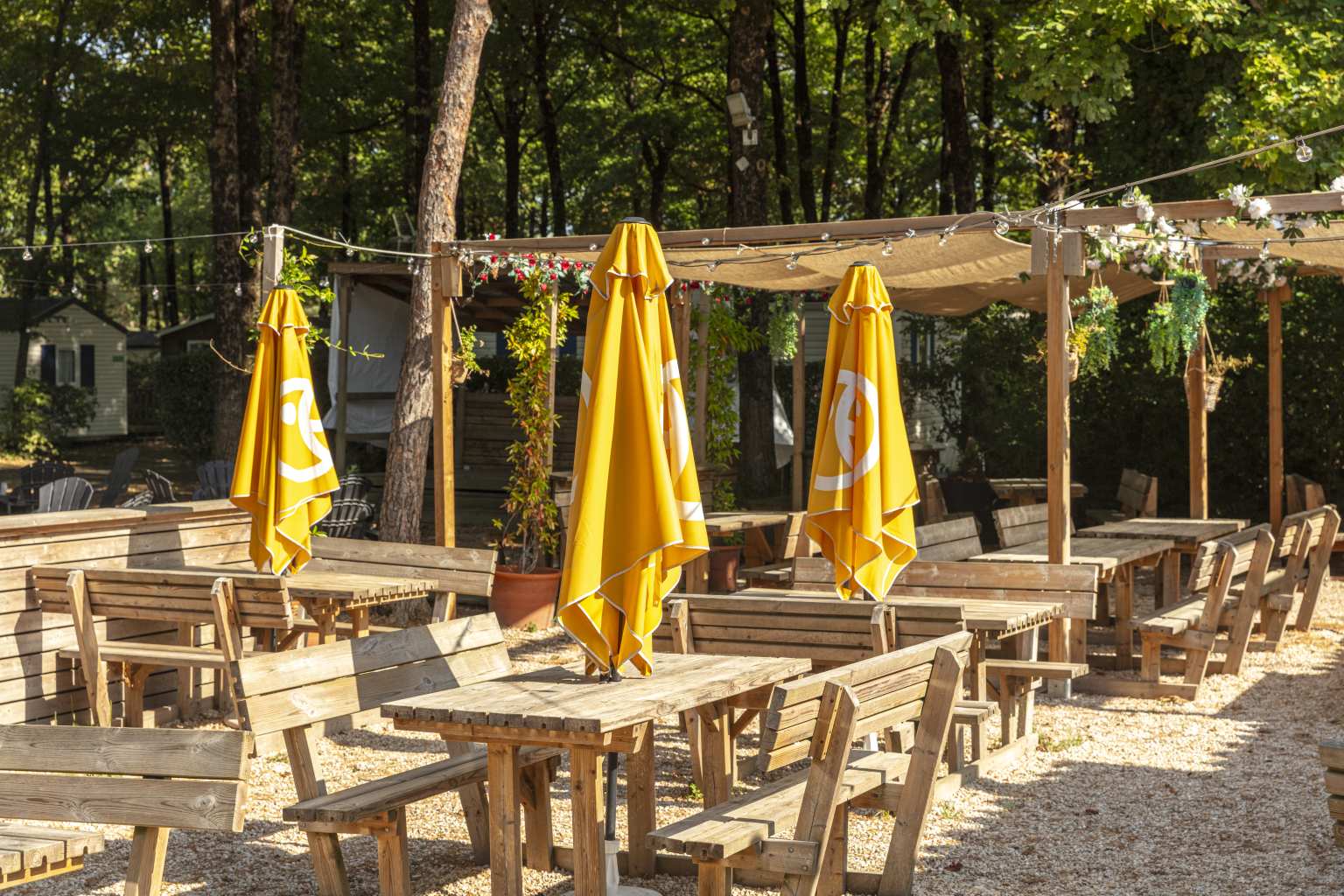 Bar terrace with wooden seating and folded parasols at Coeur de Vendée campsite in France