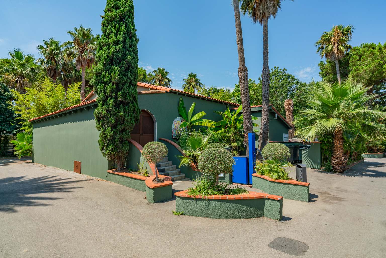 Sanititaion block surrounded by conifers, palm trees and tall trees at la Sirene campsite in the Roussillon