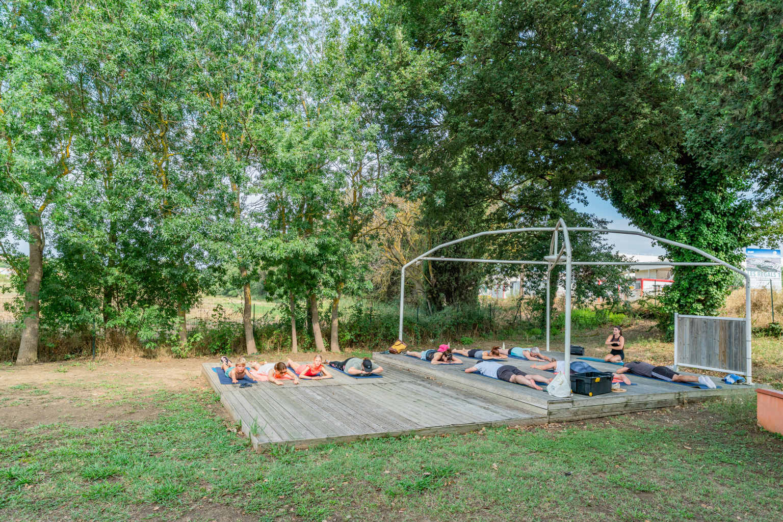 Yoga class on decking outdoors at Ma Prairie campsite in the Roussillon, France