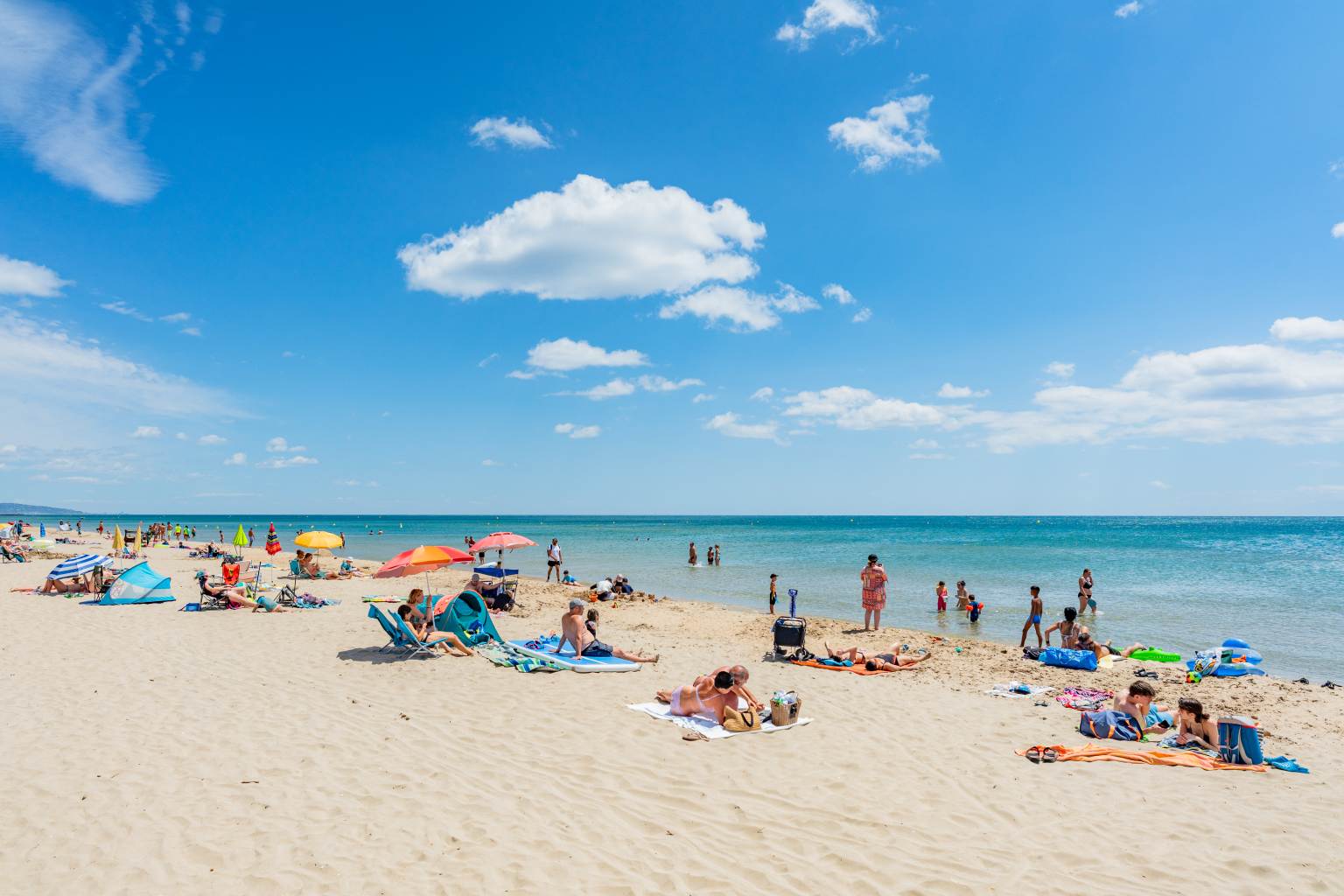 People sat on the beach and swimming at le Beach Barden campsite in the Languedoc
