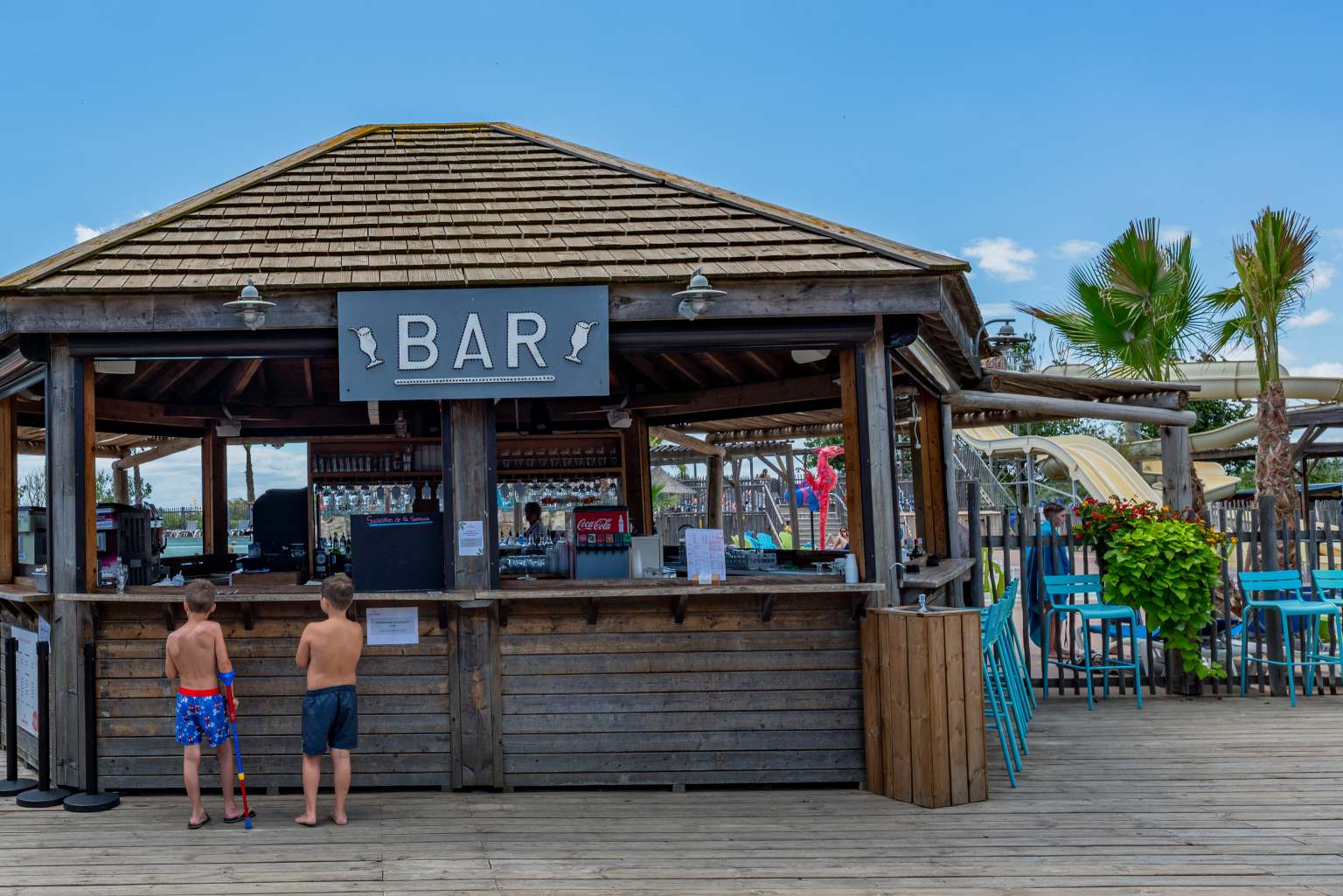 2 kids standing at the pool bar cabin at le Beach Barden campsite in the Languedoc