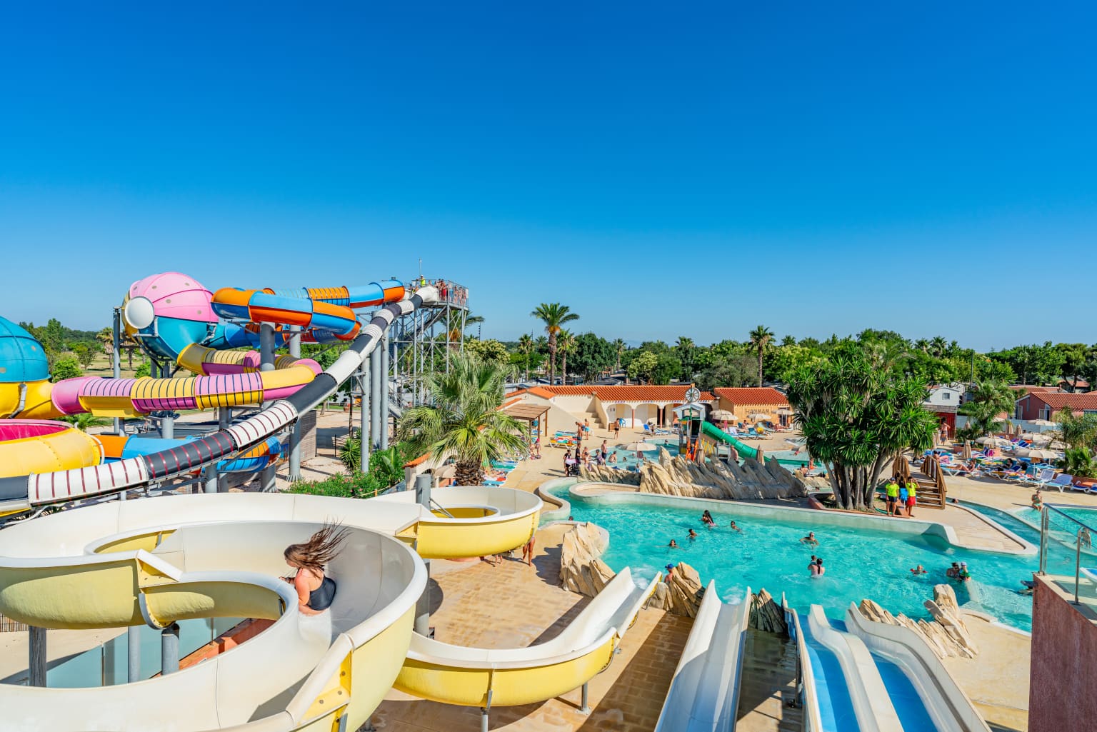 View from the top of the toboggan waterslides to lagoon pool, over to big spacebowl waterslides at le Soleil de la Mediterranee campsite, Roussillon