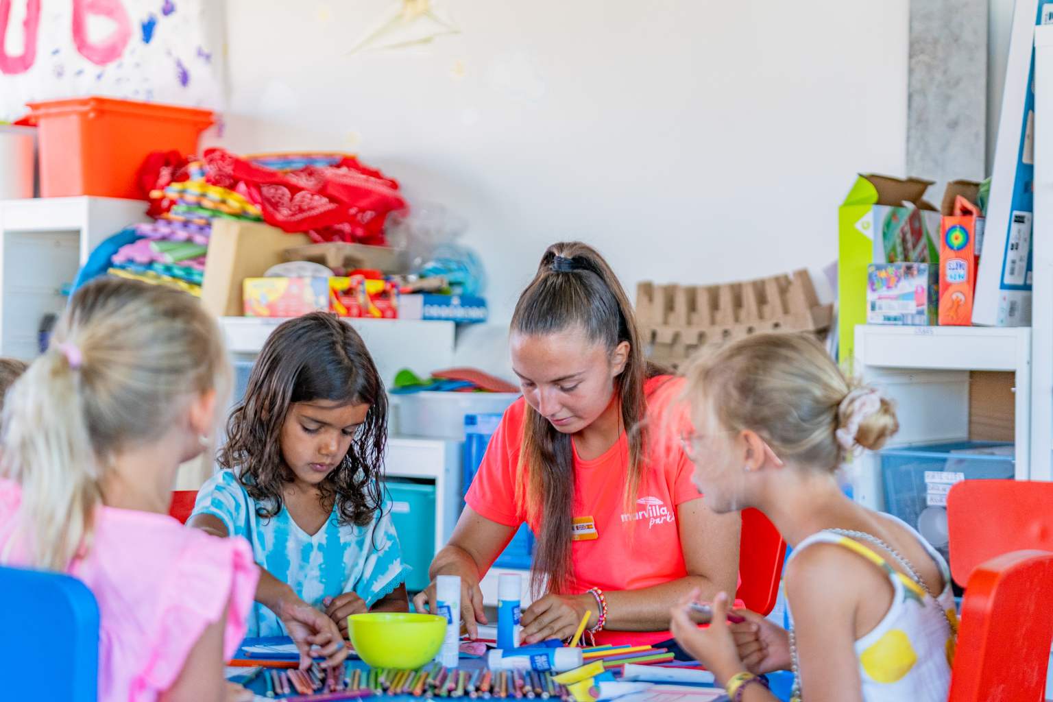 3 children sat inside with club leader, painting at the kids club at le Soleil de la Mediterranee campsite, Roussillon