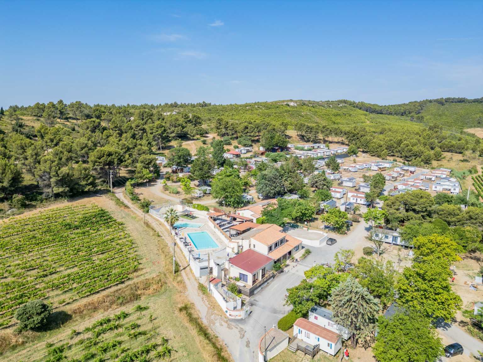 Aerial view of Borepo campsite in the Languedoc, with pool area, buildings and pitches surrouned by vineyards and trees