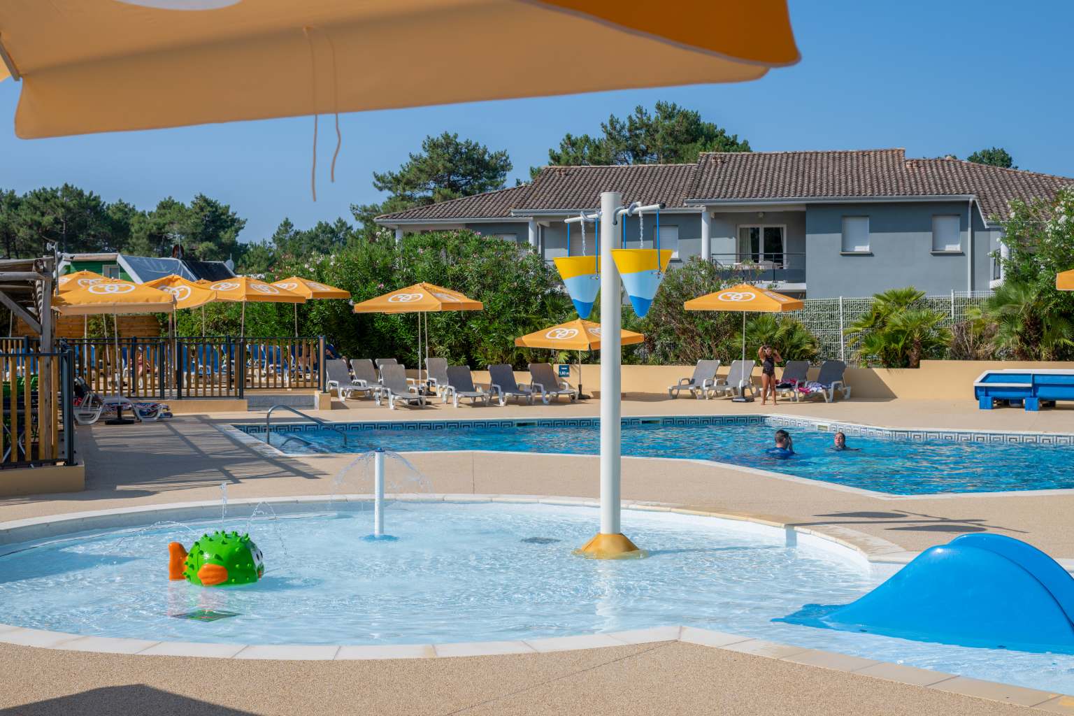 Key shaped kids pool, puffer fish water fountain and sunloungers under parasols on La Pointe du Médoc