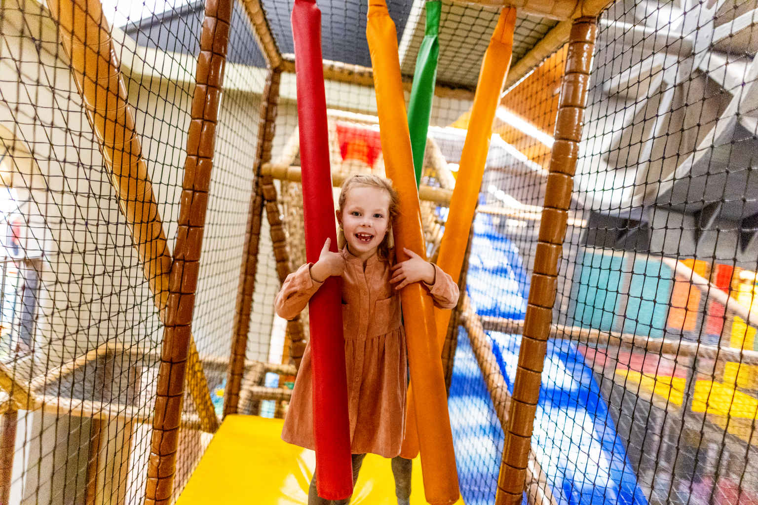Girl climbing through the nets in the indoor play centre at Vakantiepark de Bergen, Netherlands