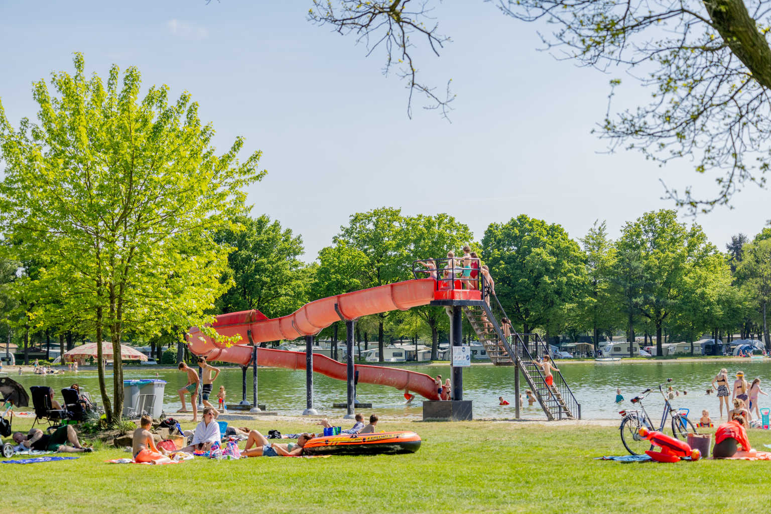 Waterchute going in the lake, and sunbathers on the lawn, at Vakantiepark de Bergen campsite in the Netherlands