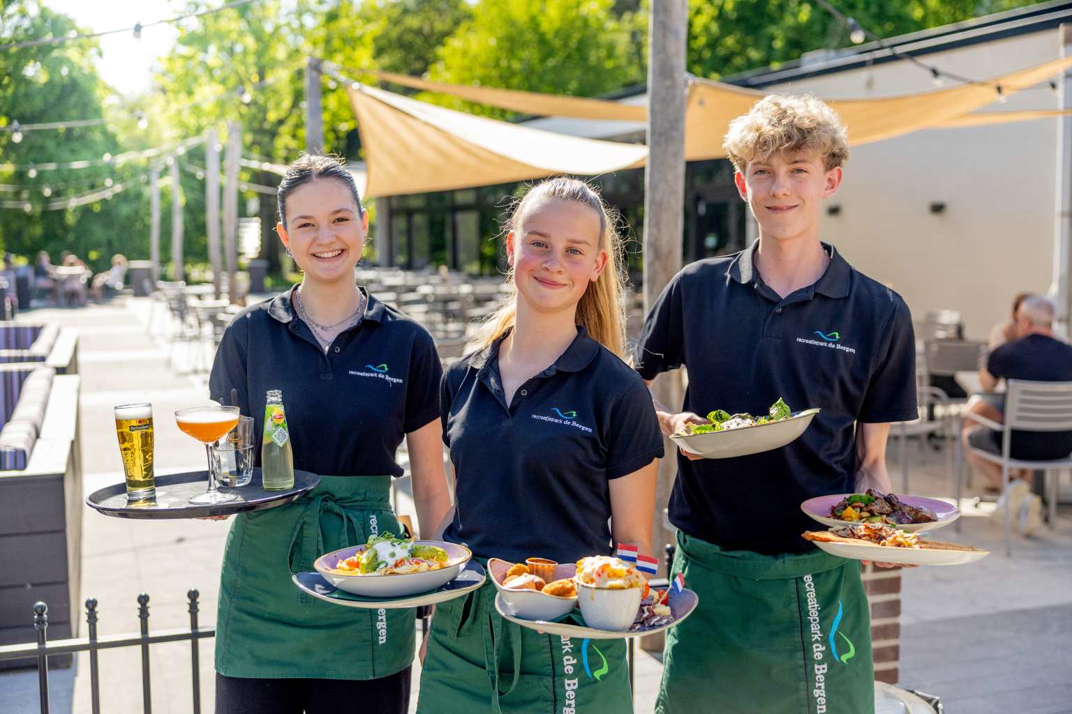 Waiters carrying plates on the outdoor terraces at Vakantiepark de Bergen campsite, Netherlands