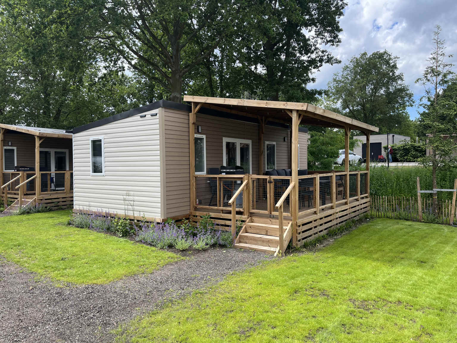 Holiday home with covered decking and grass area at Klein Canada campsite in the Netherlands