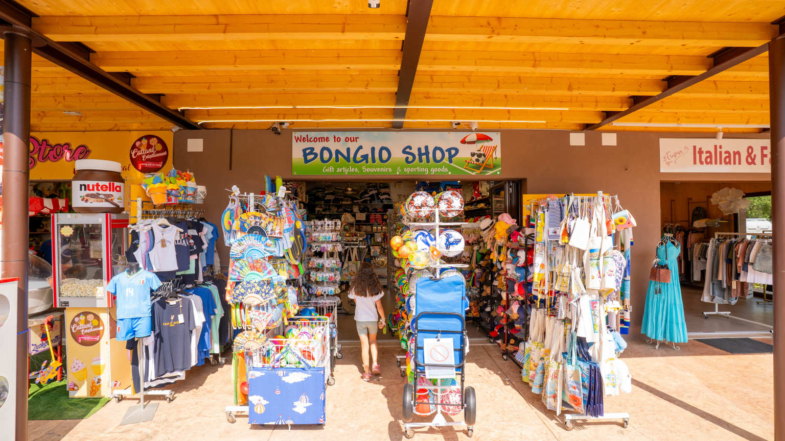 Tee shirts, bags and gifts on stands outside the gift shop at Bella Italia campsite, Lake Garda