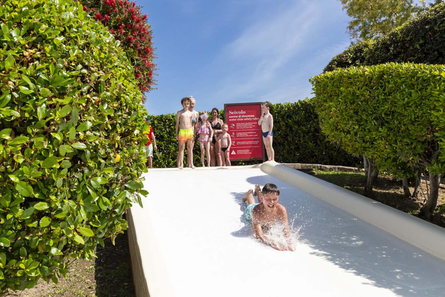 Child sliding down the water slope into the pool at Camping Fabulous Village, near Rome