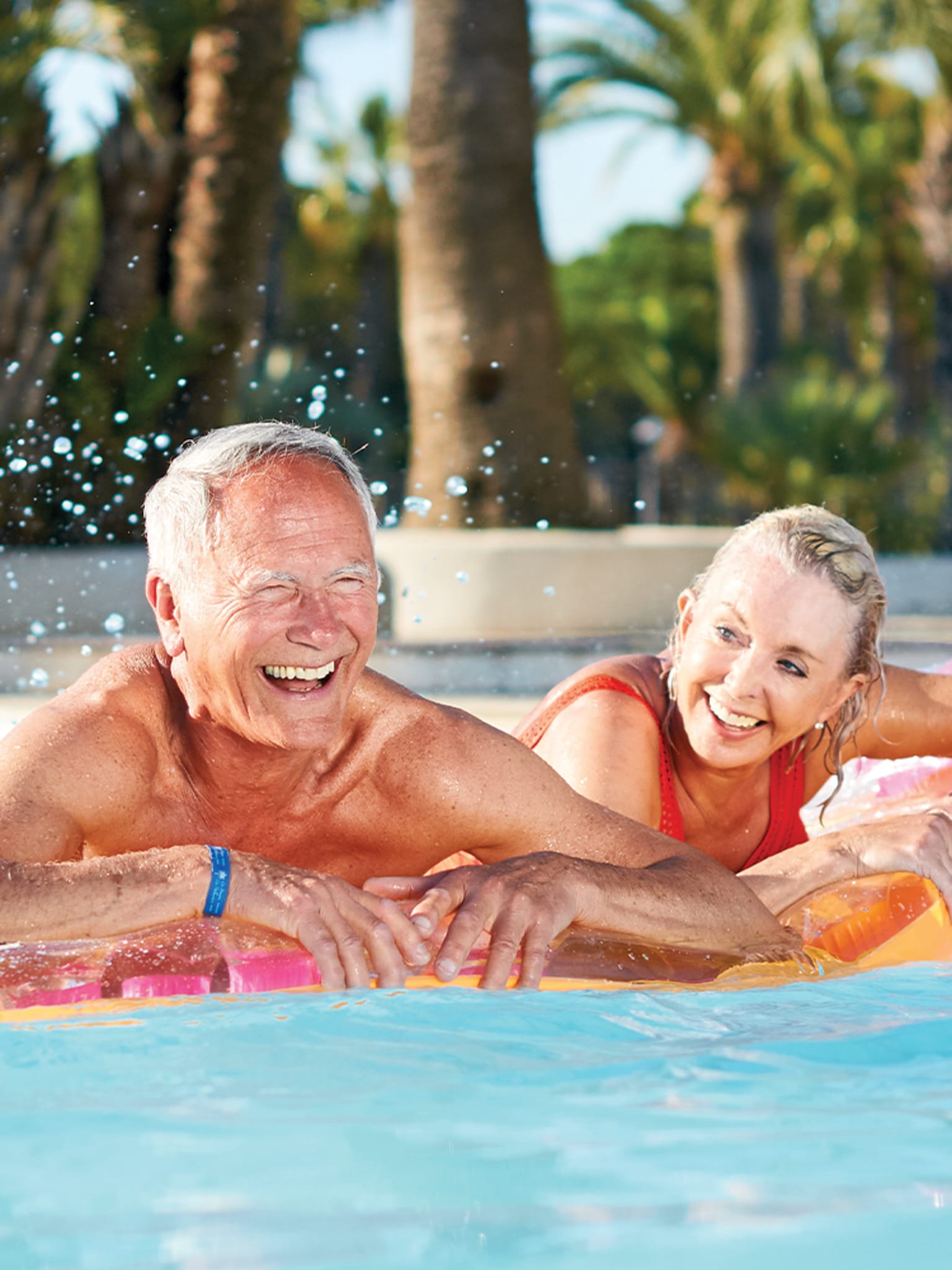 Senioren vergnügen sich im Pool auf einer Luftmatratze