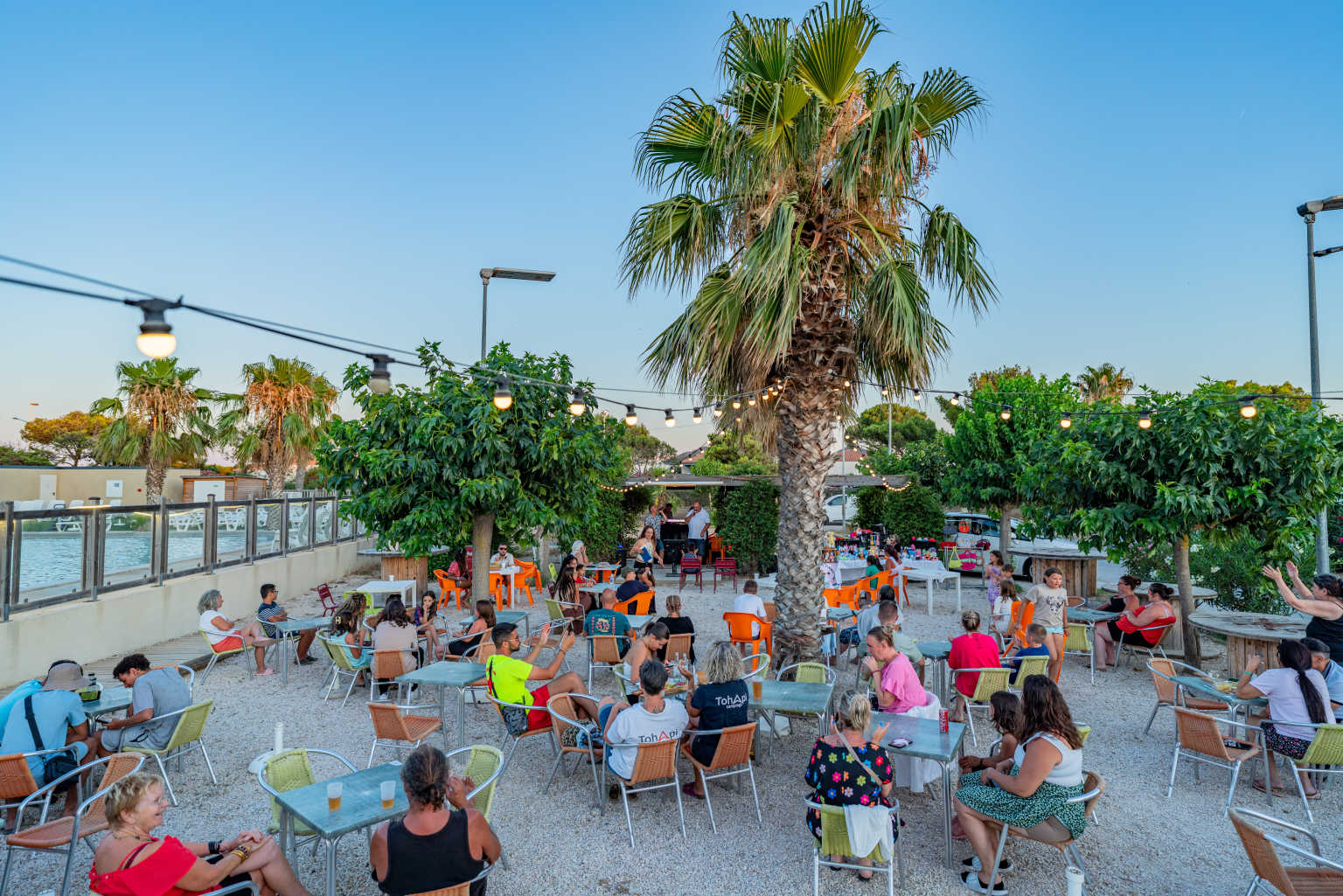 Evening customers drinking and relaxting at the bar terrace at Novela Port La Nouvelle campsite, Languedoc